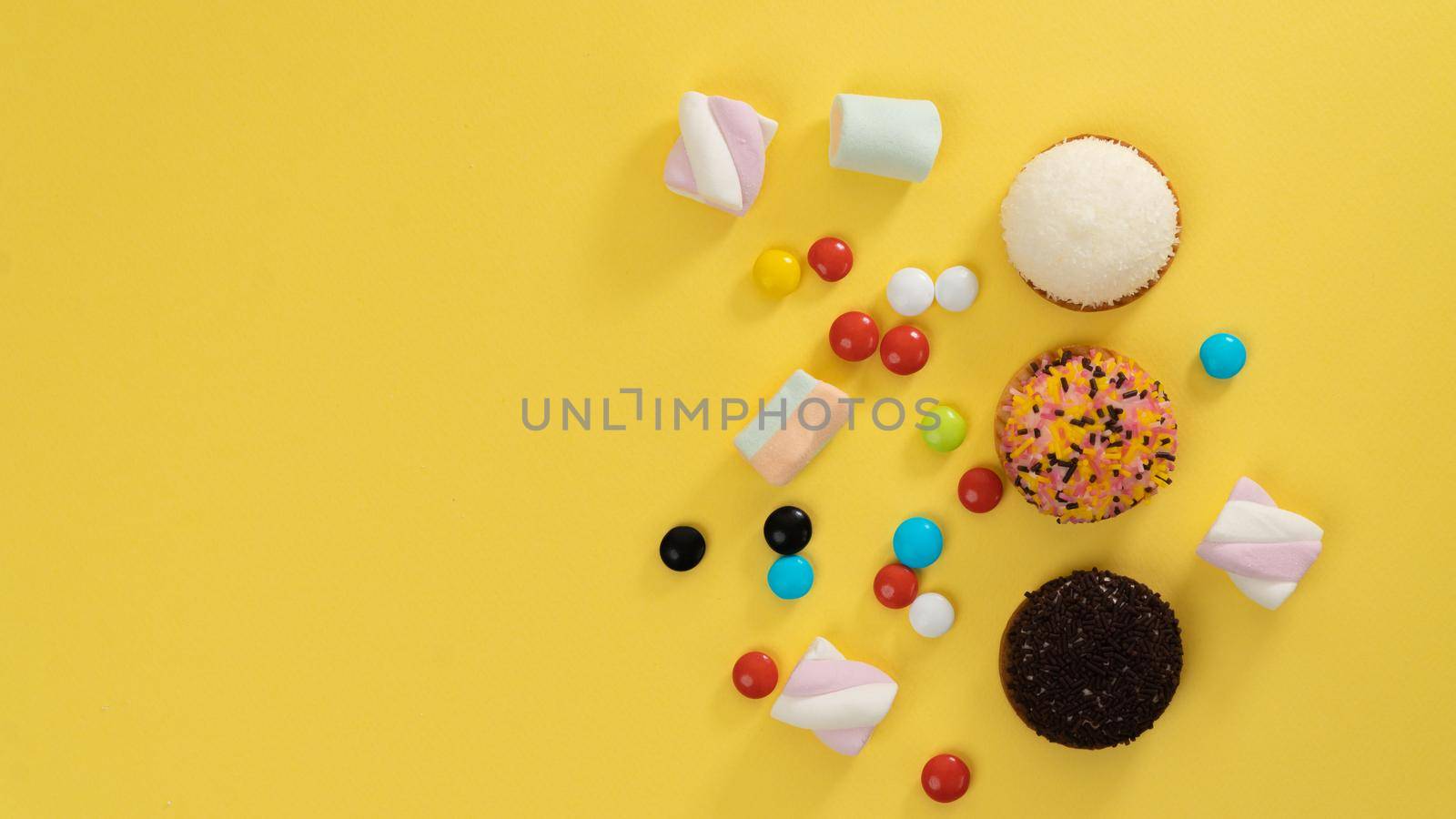 Cakes, marshmallows, sweets on a yellow background - sweets and space for text. High quality photo