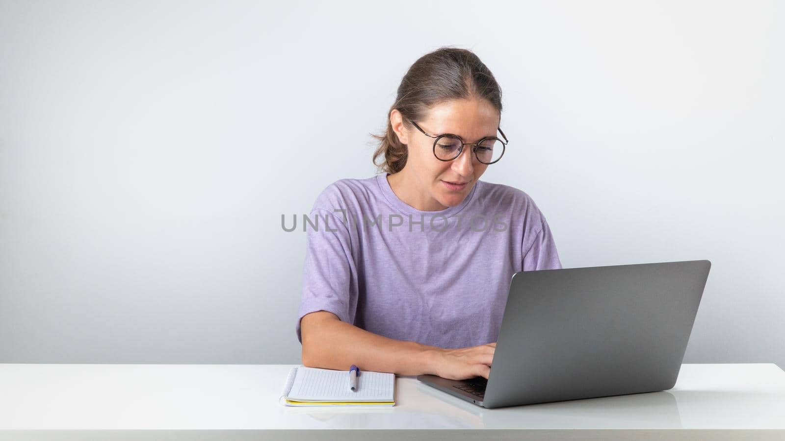 A woman sits at a laptop and searches for information on the Internet, corresponds, studies or works by voktybre