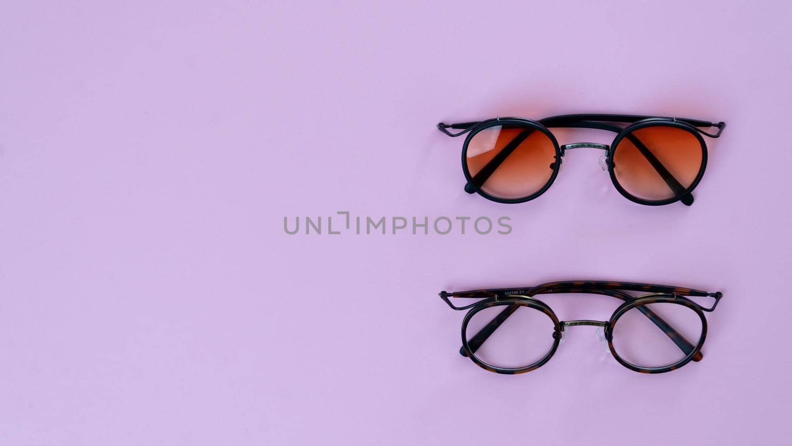 Eyeglasses and sunglasses on a purple background with space for text by voktybre