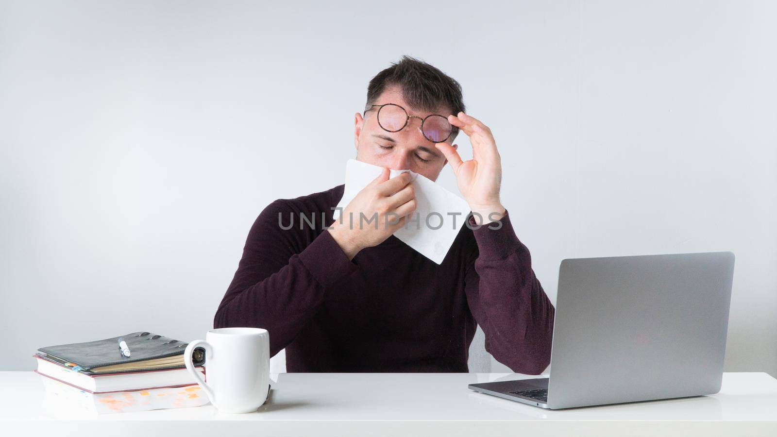 A man wipes his nose with a napkin - runny nose, flu, cold at work, get sick in the office. High quality photo