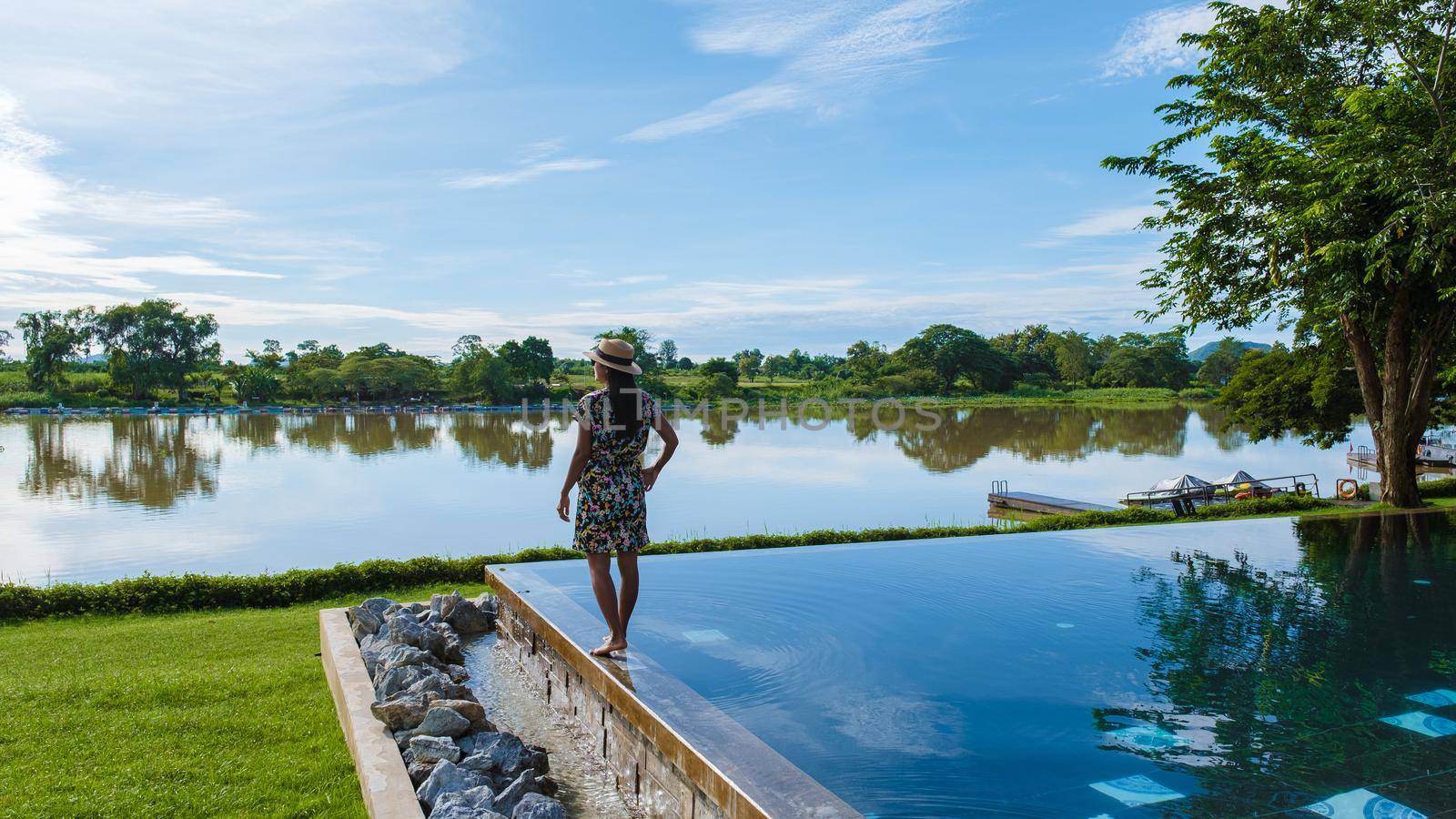 Luxury swimming pool by the River Kwai in Thailand. Women looking at river on the edge of the pool at the river side of the River Kwai Kanchanaburi