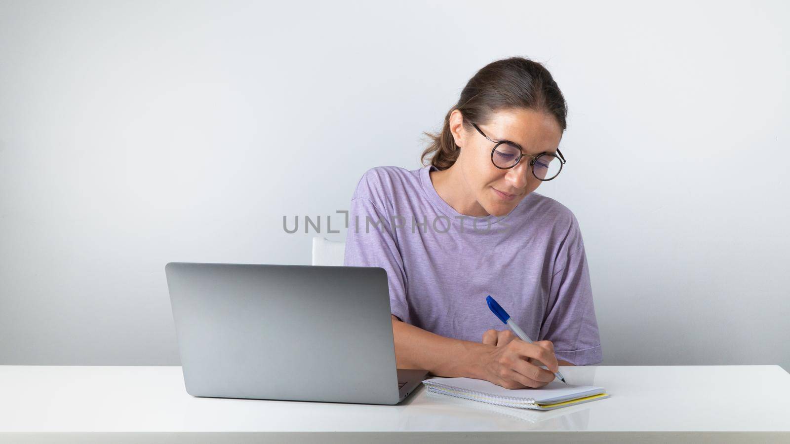 A student at a laptop makes notes in a notebook, studies. High quality photo