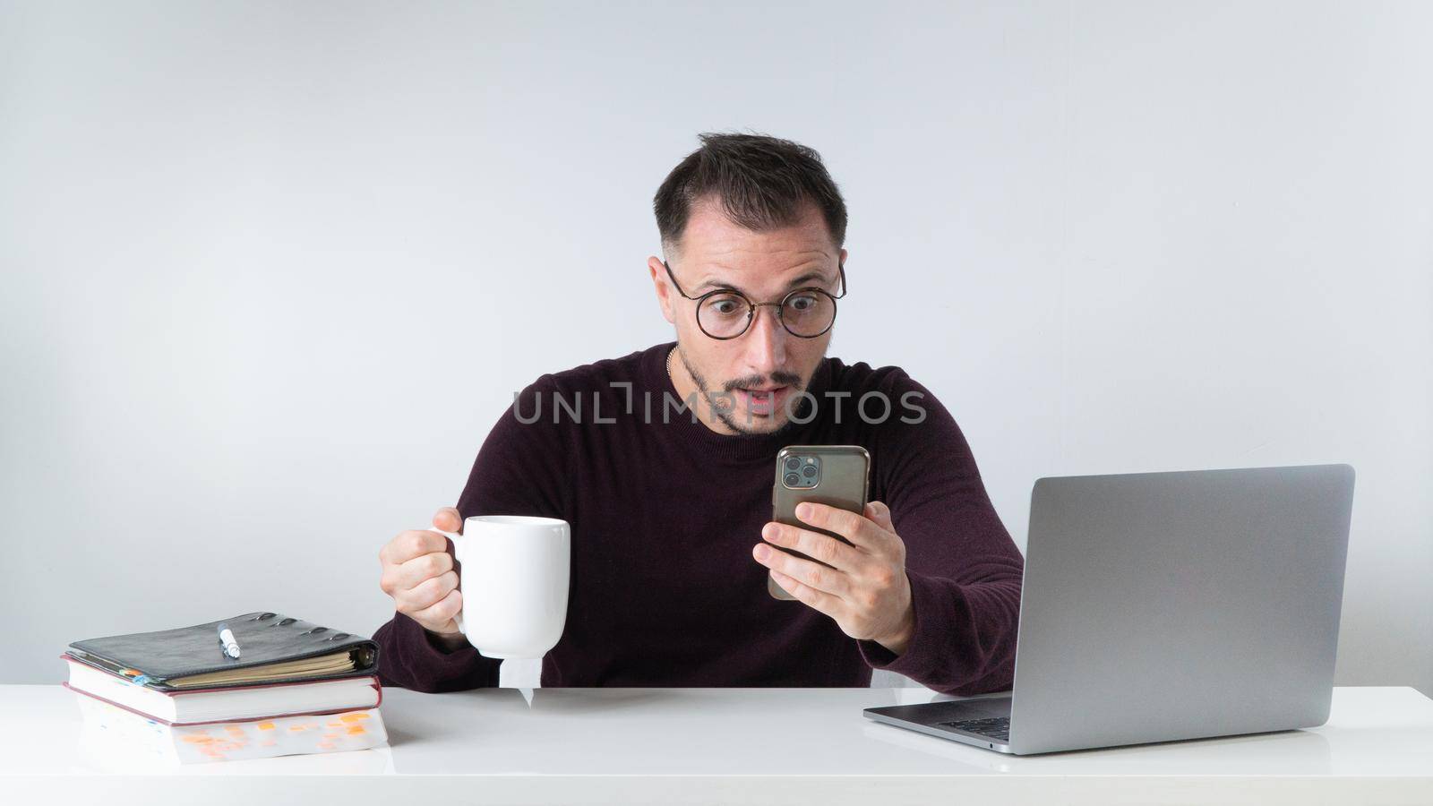 The man was surprised by the information in the phone - workplace, office. High quality photo