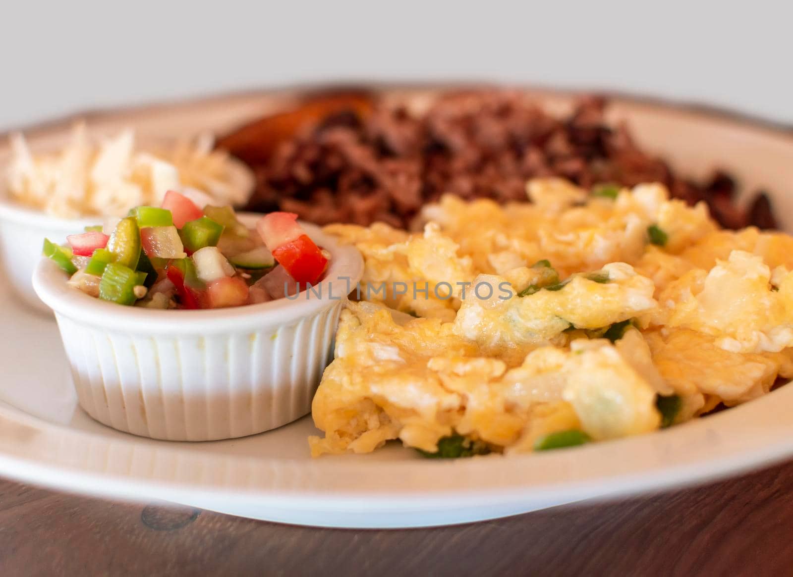 Gallopinto breakfast served on table, gallopinto with fried eggs with pico de gallo on wooden table. Traditional gallopinto dish with fried eggs and pico de gallo served on the table by isaiphoto