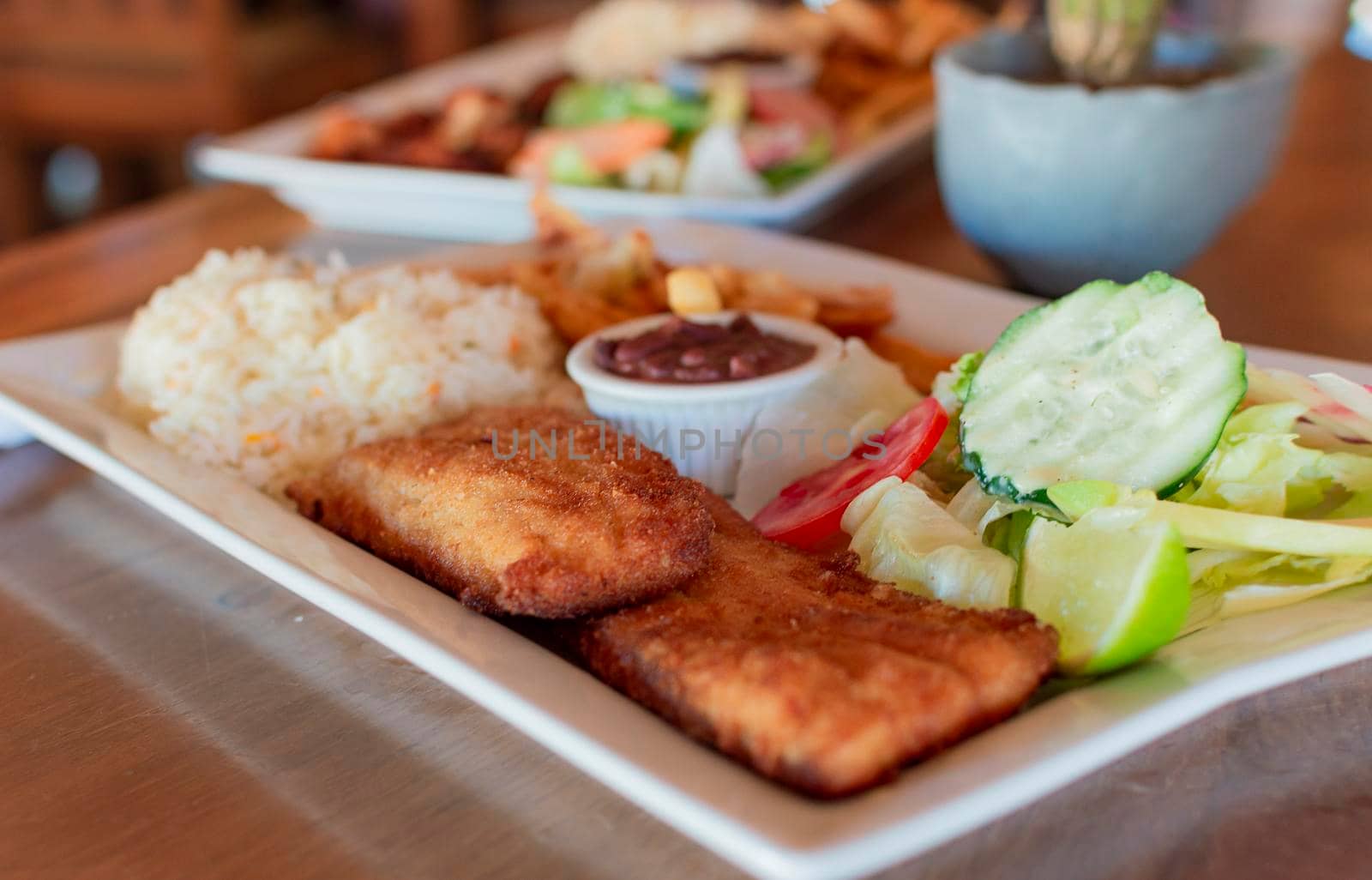 Gourmet food fried fish fillet with salad rice served on wooden table, Close up of fried fish fillet with rice and salad served on table with copy space. gourmet food fried fish fillet