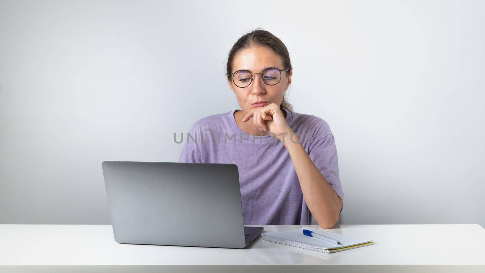 Brooding girl at a laptop with a notebook and a pen - remote learning, online education by voktybre