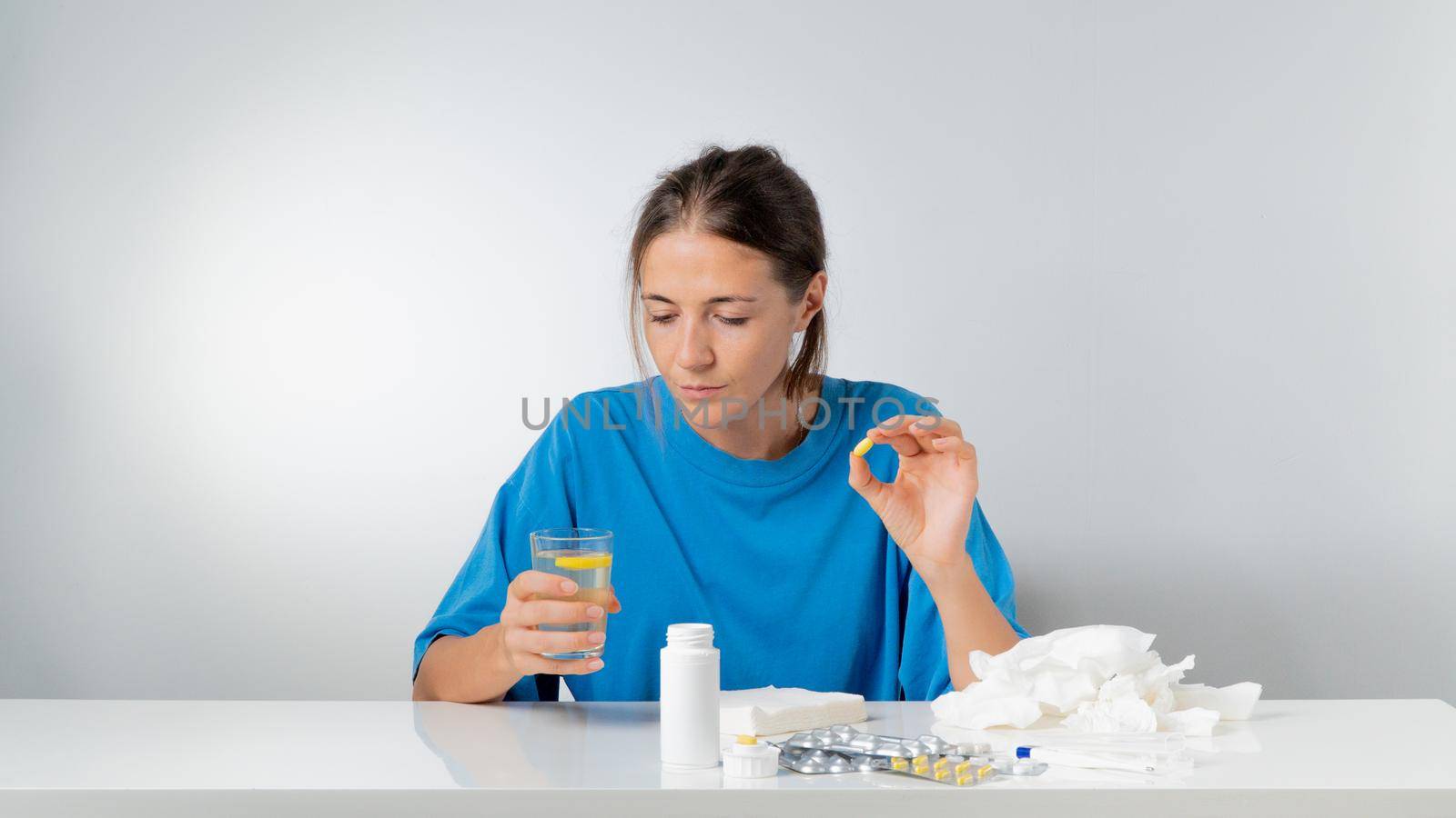 Woman with a pill in her hand and a glass of water - treatment for colds and flu. High quality photo