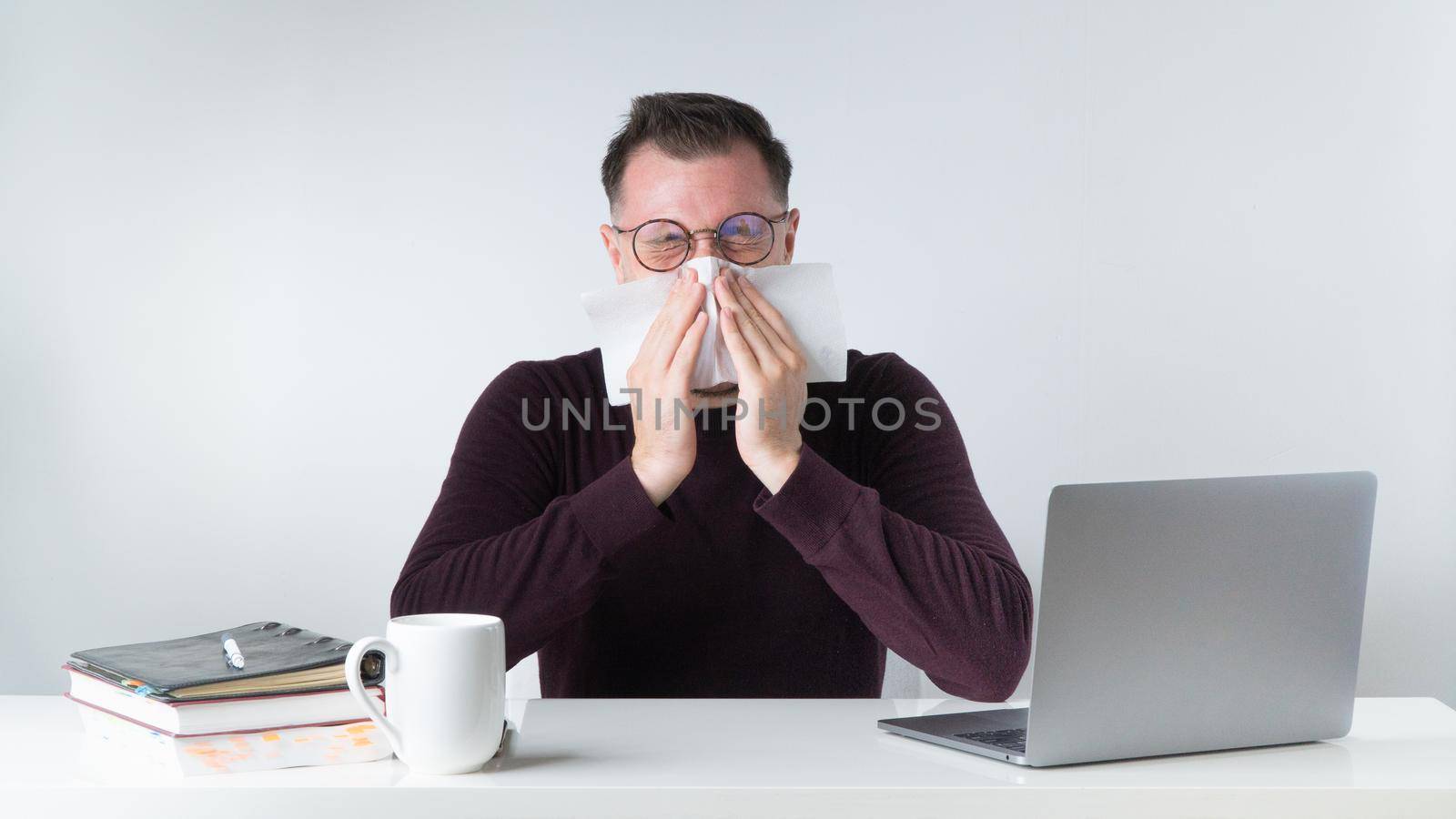 A man sneezes or blows his nose at the workplace in the office by voktybre