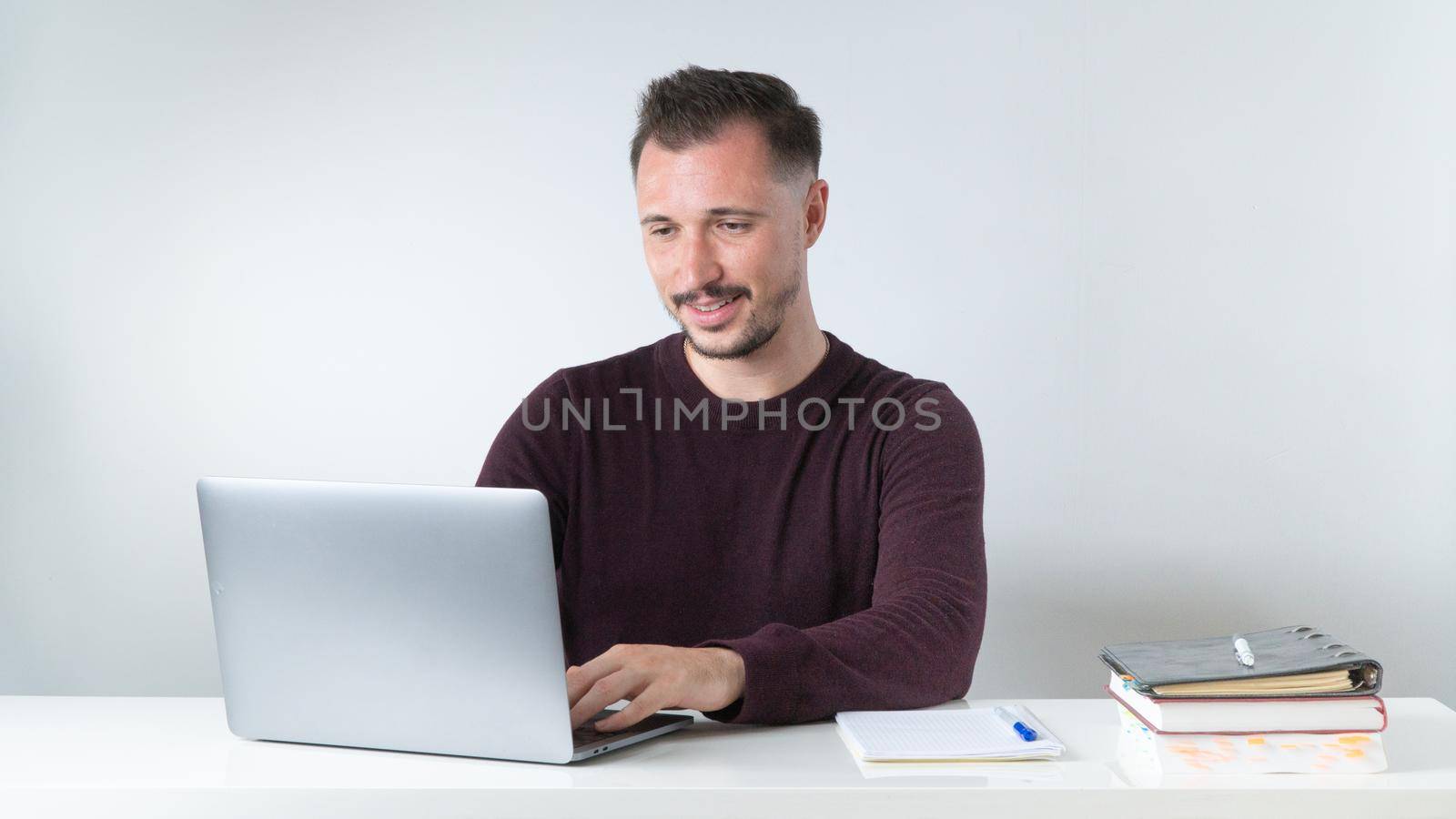 A man types in a laptop at a desk in the office or at a remote work by voktybre