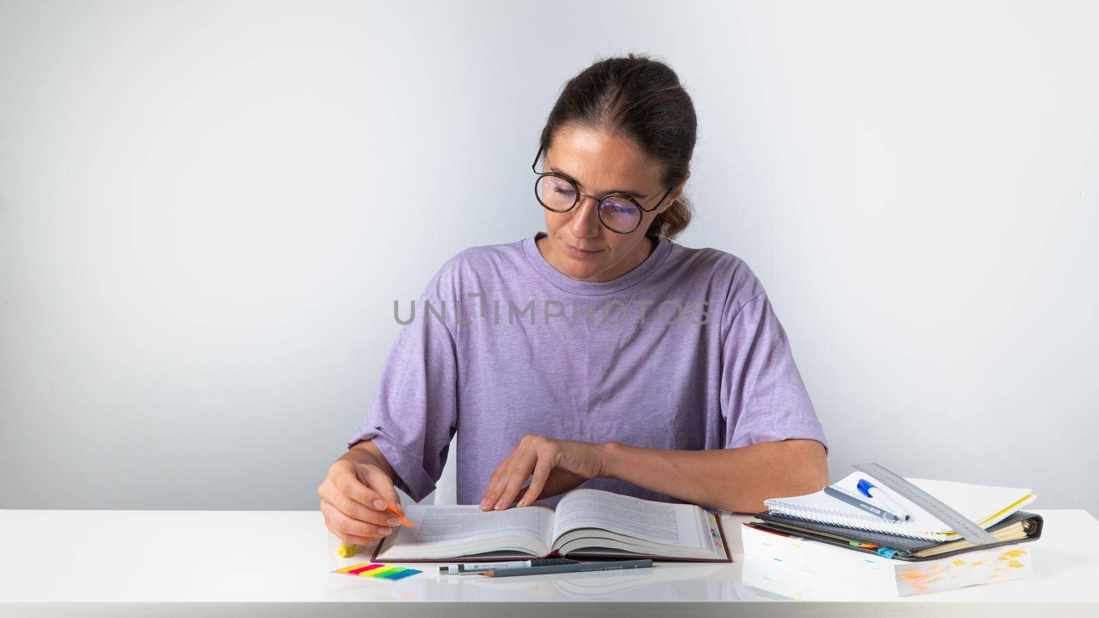 The student makes notes and bookmarks in the textbook. High quality photo