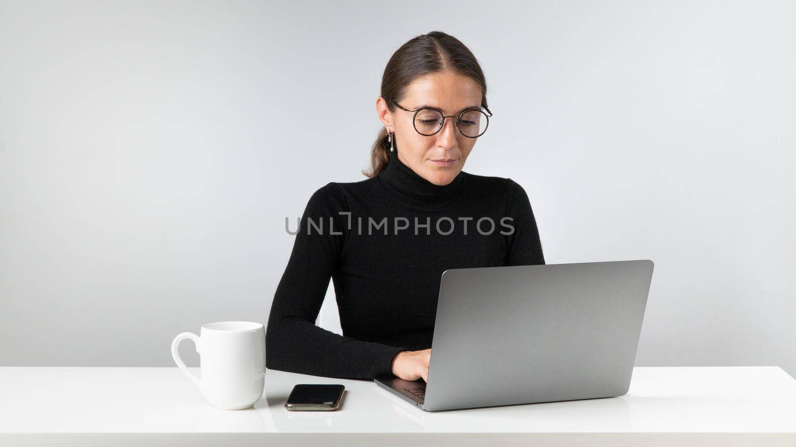 A woman works at a laptop with a cup of tea or coffee by voktybre