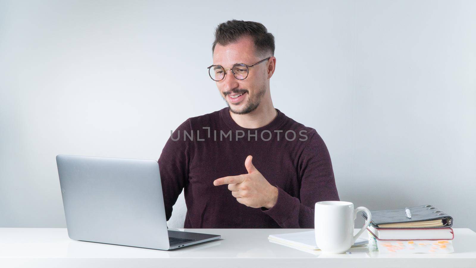 A man with glasses communicates via video call on a laptop, an online conference at work by voktybre