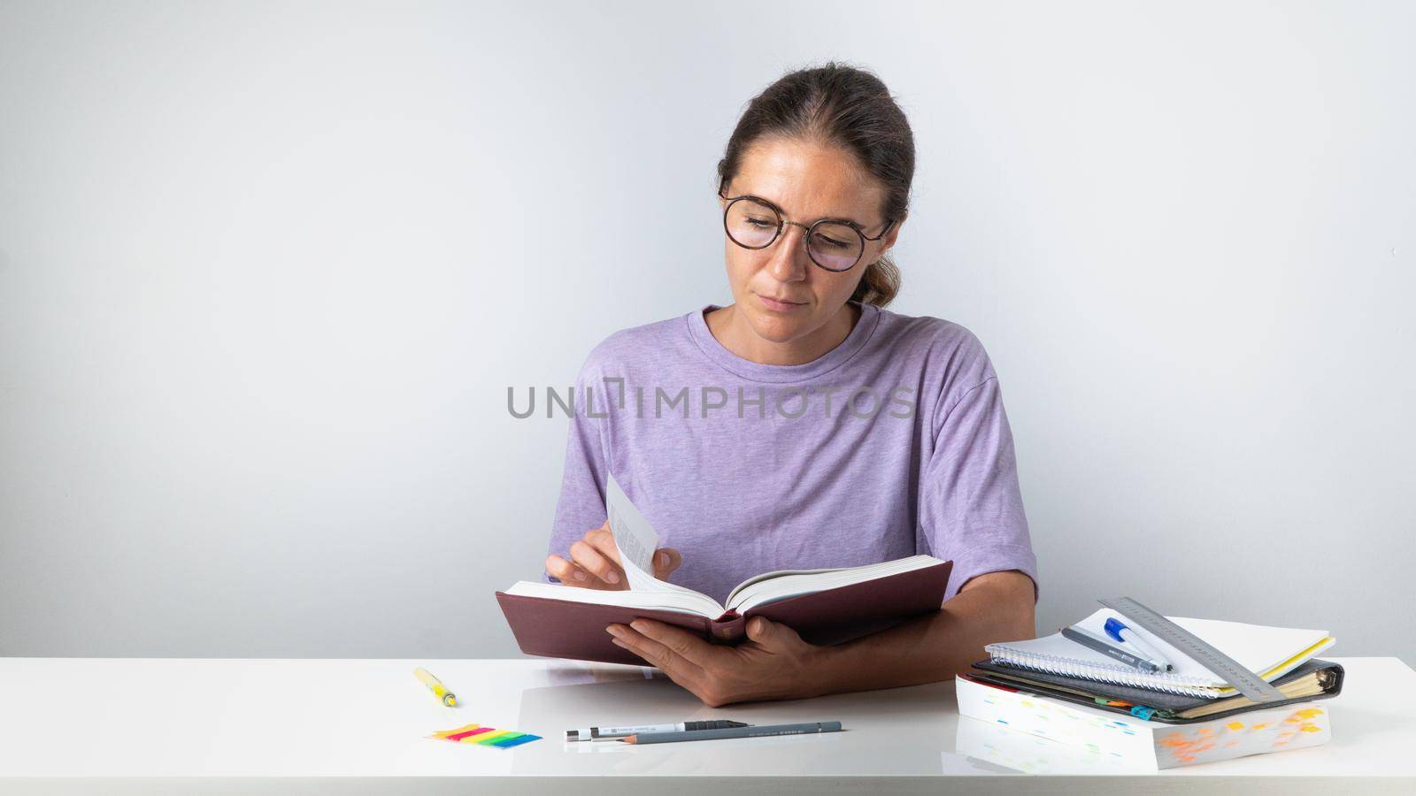 Studying the material, a student with glasses reads a textbook at the table by voktybre