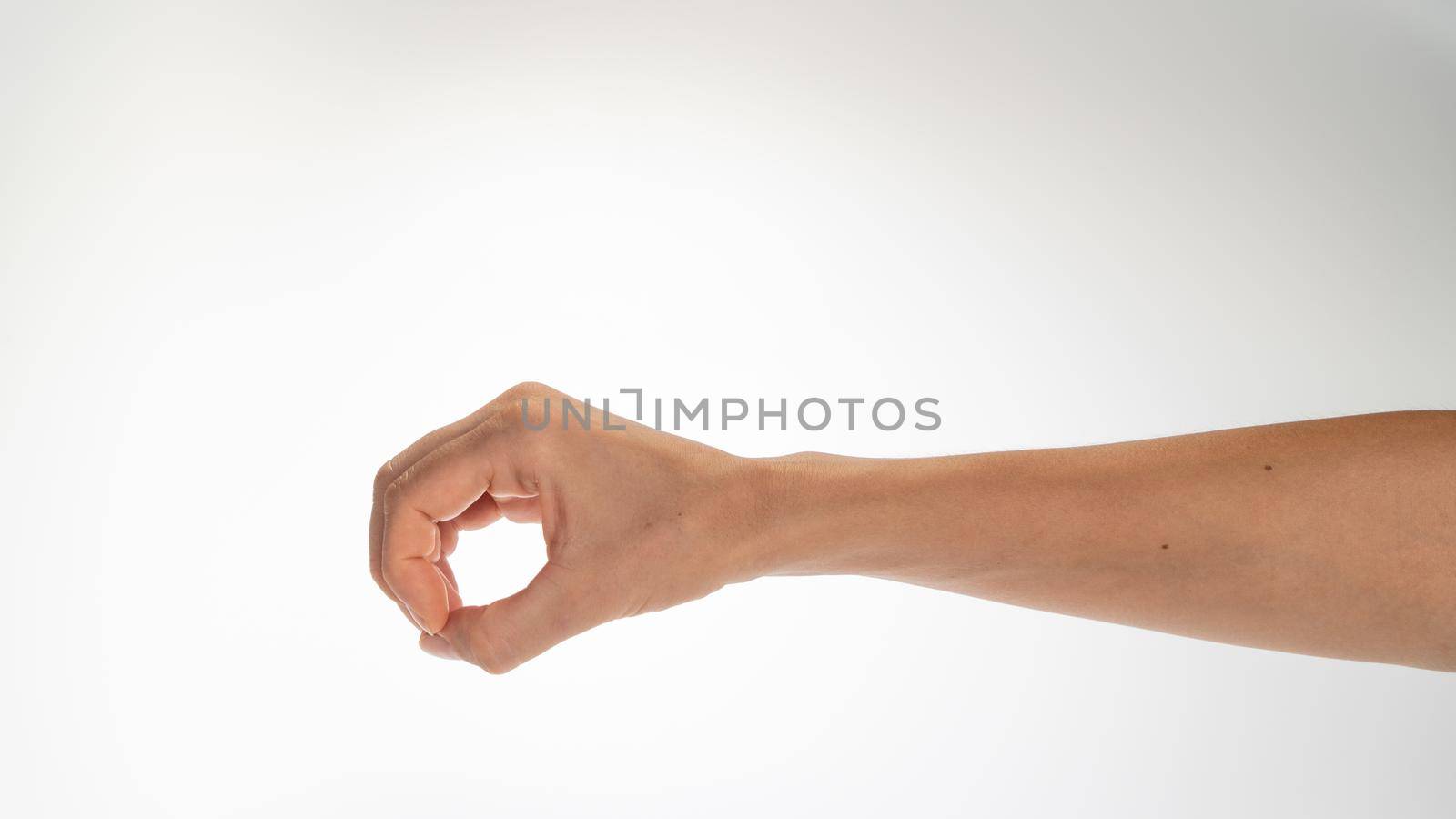 Hand woman gesture fingers clenched into a ring holding a cylindrical object. High quality photo