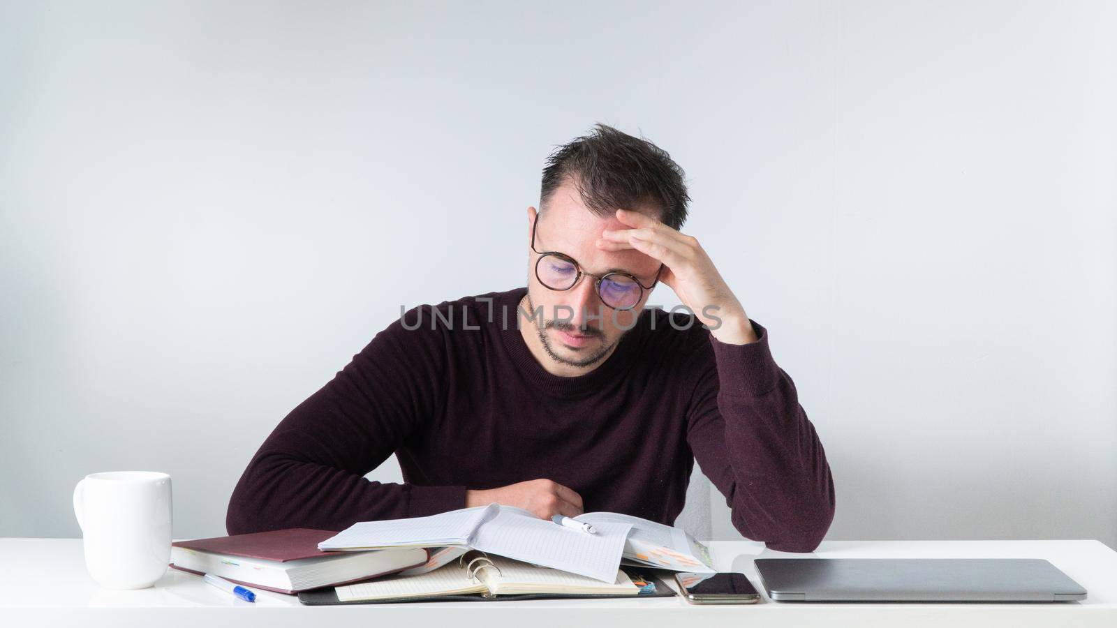 A man with glasses at his desk thinks about a task in the office - to complete the task by voktybre