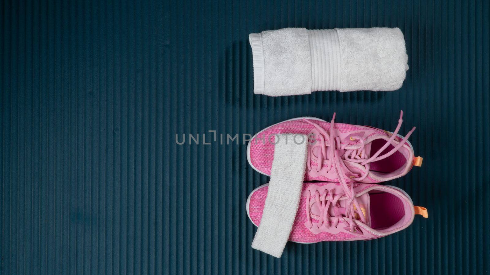 Sneakers, rolled up towel and Buff on the sports mat - space for text by voktybre