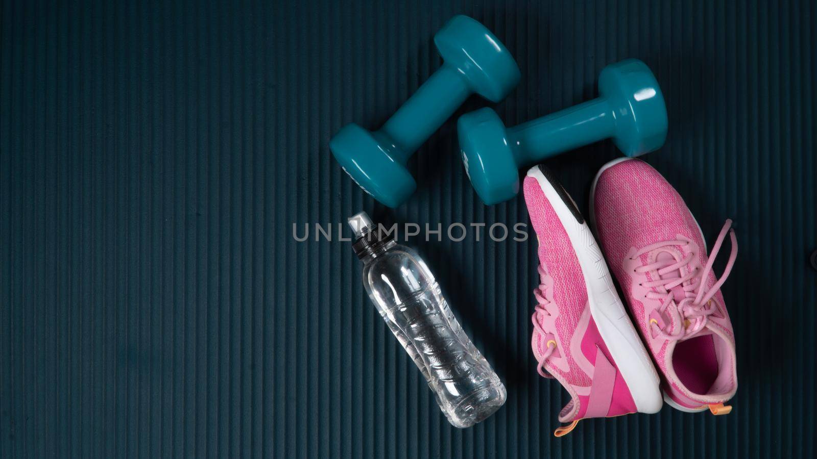 Set for athlete - women's sneakers, dumbbells and a water bottle with space for text by voktybre