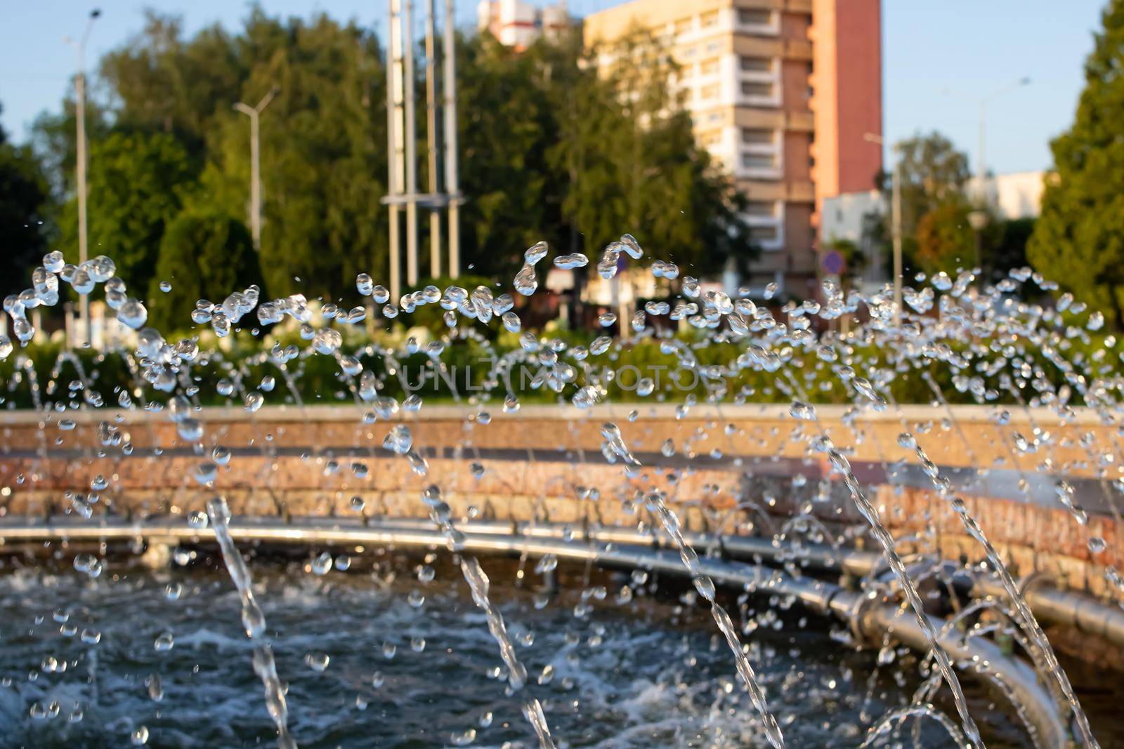 Splashes of water in the fountain at sunset close up