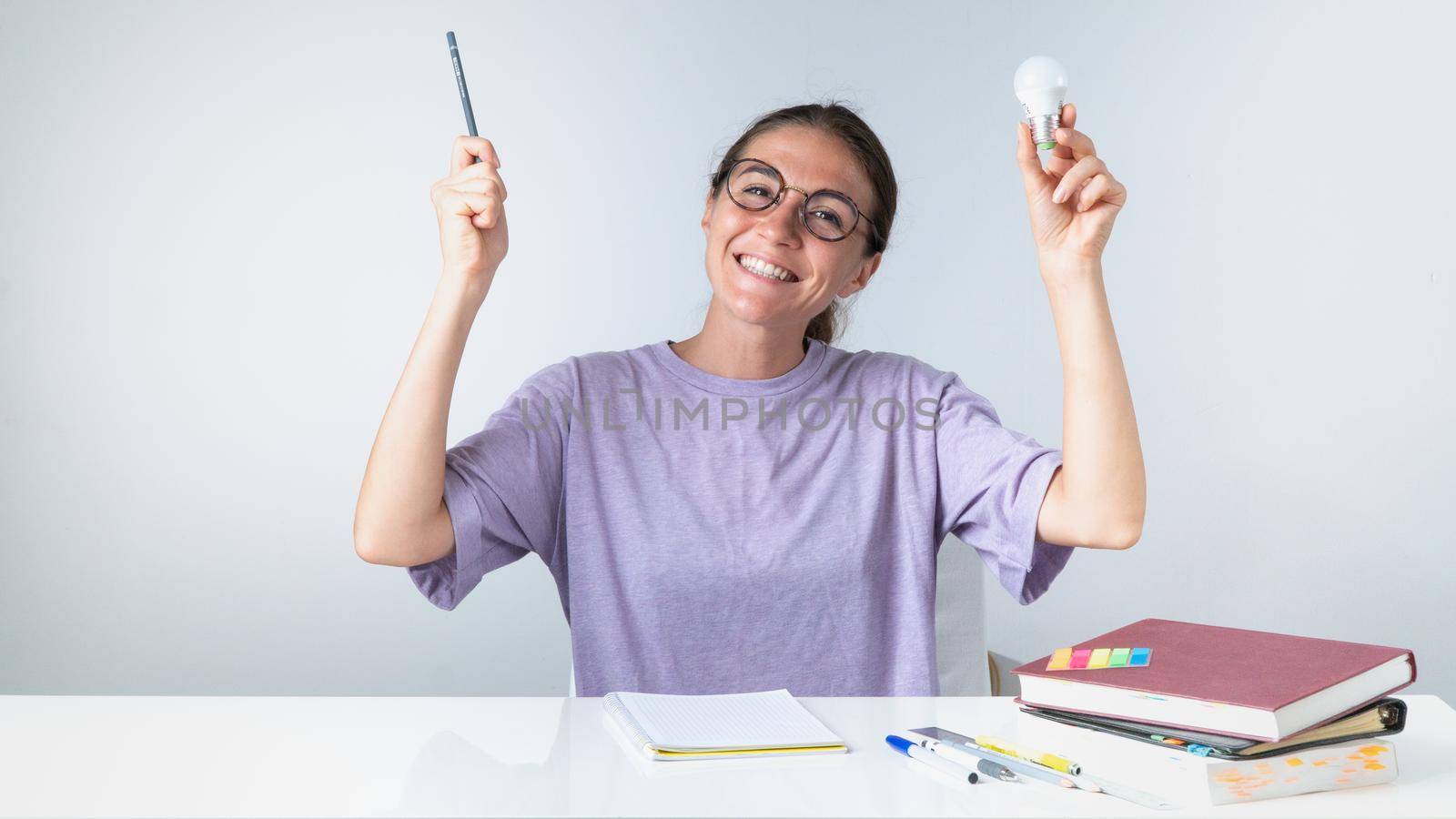 A joyful student with a pencil and a light bulb, an idea or answer came during her studies. High quality photo