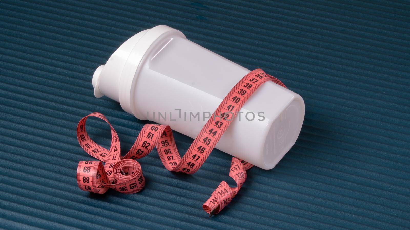 Shaker with measuring tape centimeter on the mat for training, sports background, yoga by voktybre