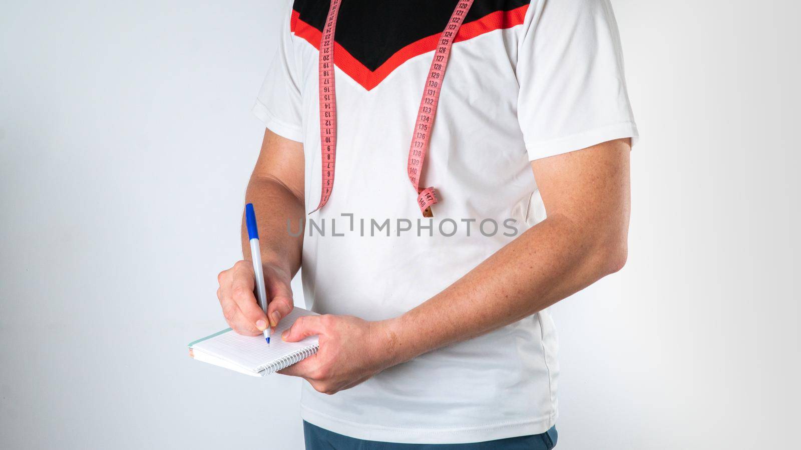 A man with a notebook and measuring tape, a trainer nutritionist makes up the diet and sports by voktybre