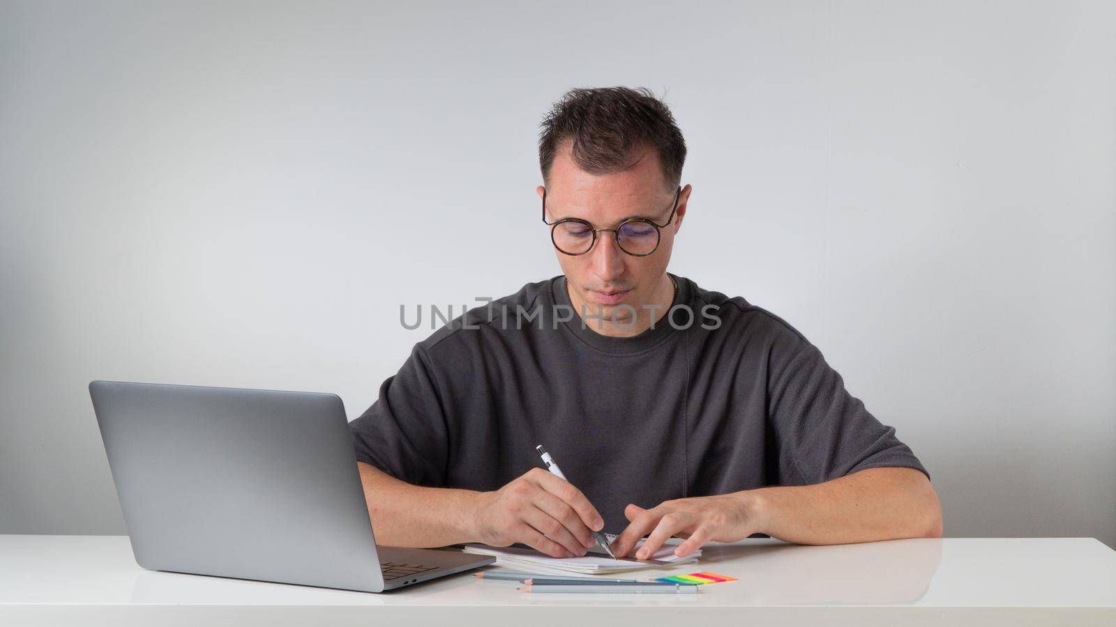 A student with glasses learns with a laptop and notebooks. High quality photo