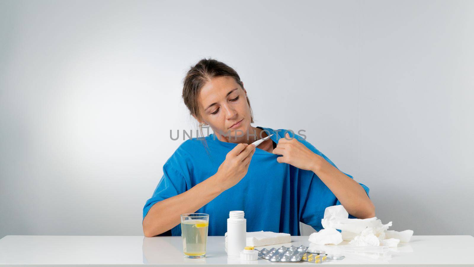 A woman takes her temperature during a flu illness - treatment. High quality photo
