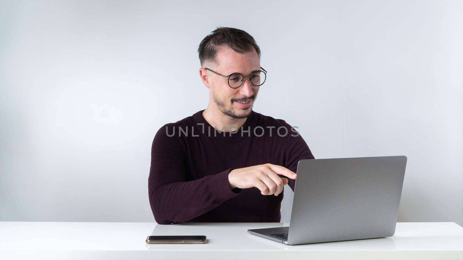 A man communicates via video call in a laptop at his desk by voktybre