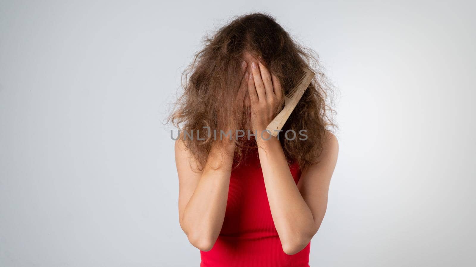 The woman covered her face with her hands - stress due to naughty, brittle and tangled hair. High quality photo