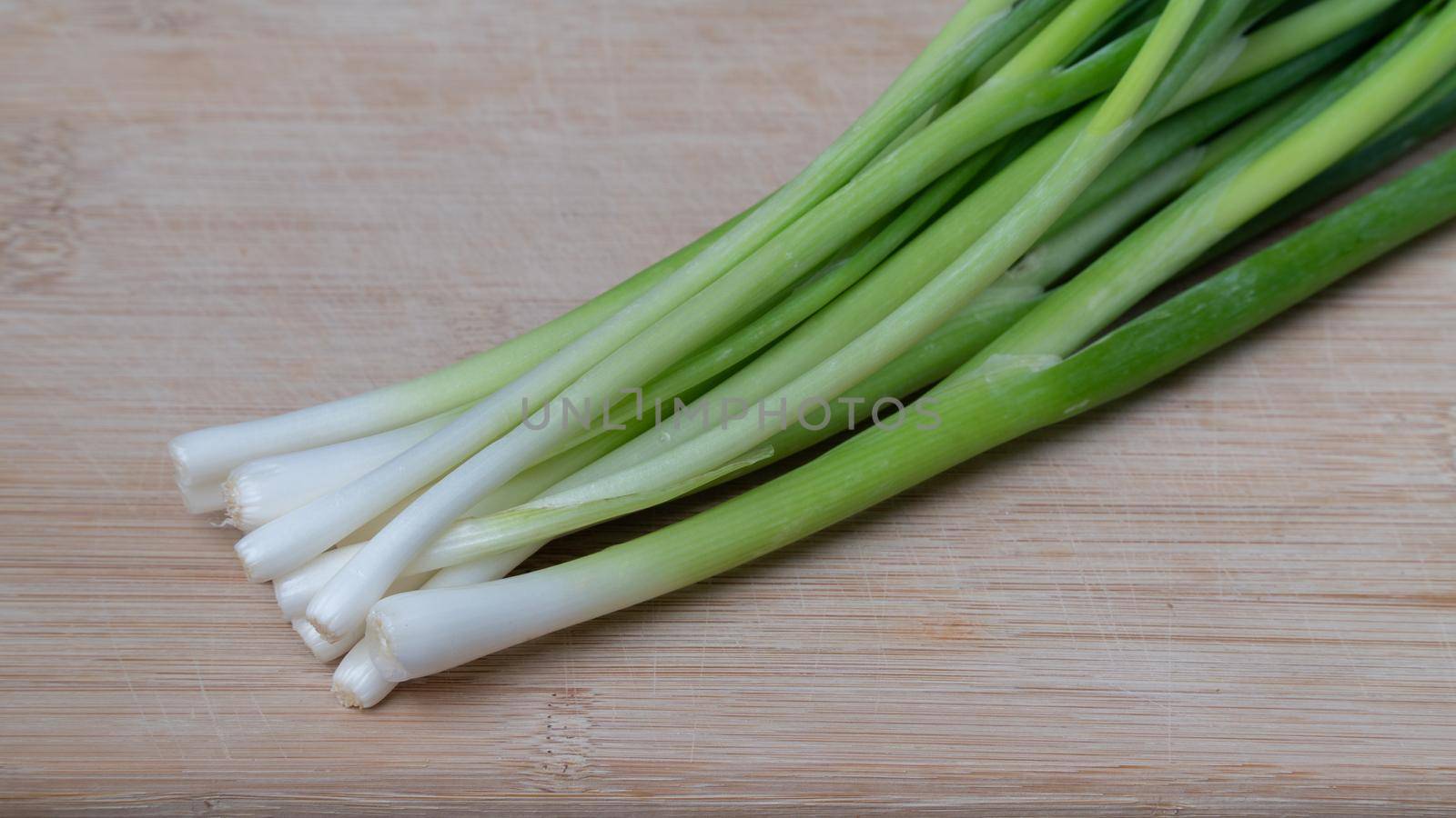 Green onion feathers lie on a wooden board close-up of greens by voktybre