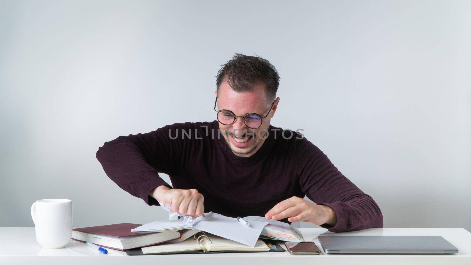 Angry man working in office tears out a piece of paper from a notebook - wrong entries by voktybre