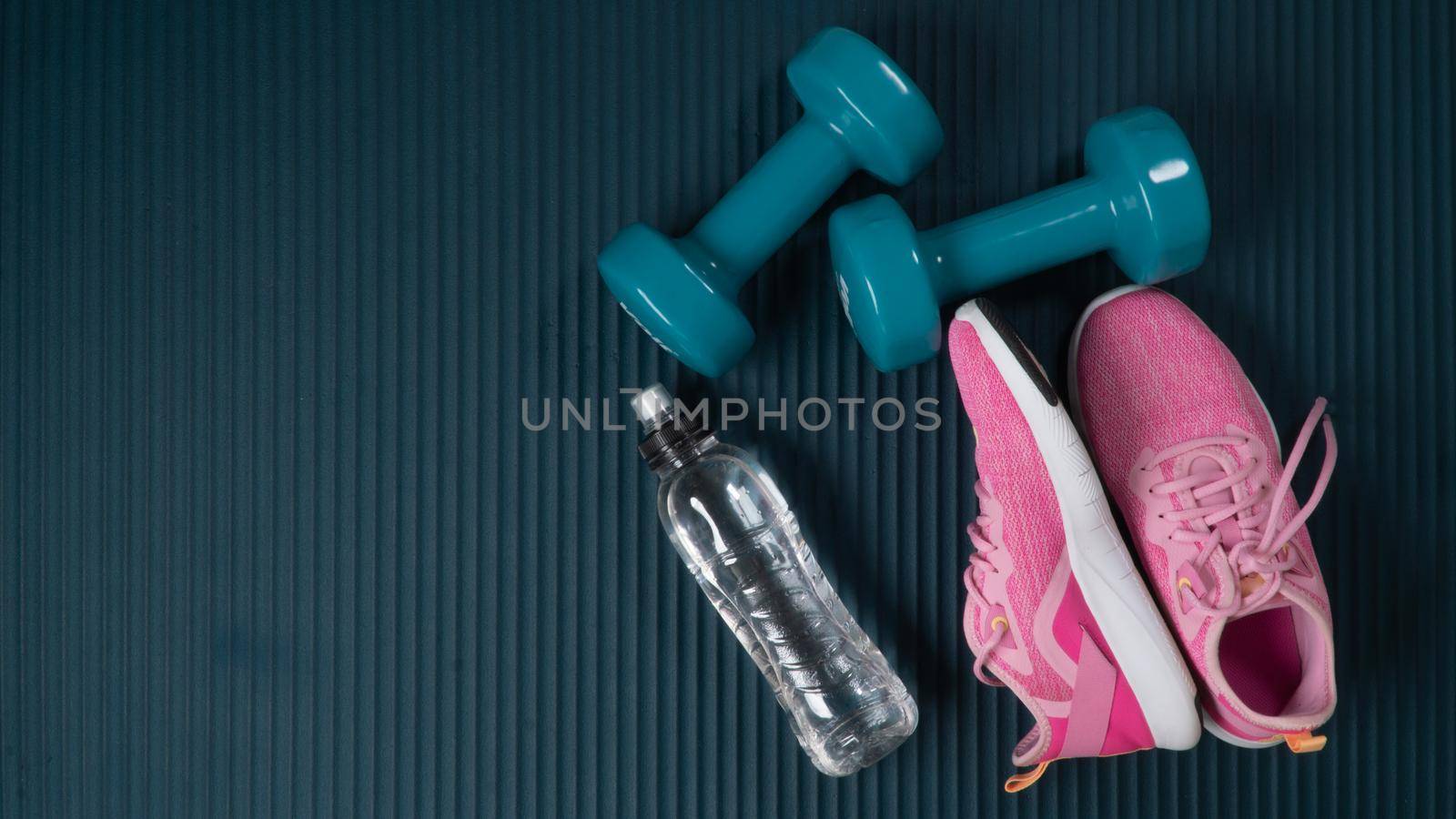 Sports equipment for training in the hall - water, dumbbells and sneakers on the sports mat. High quality photo
