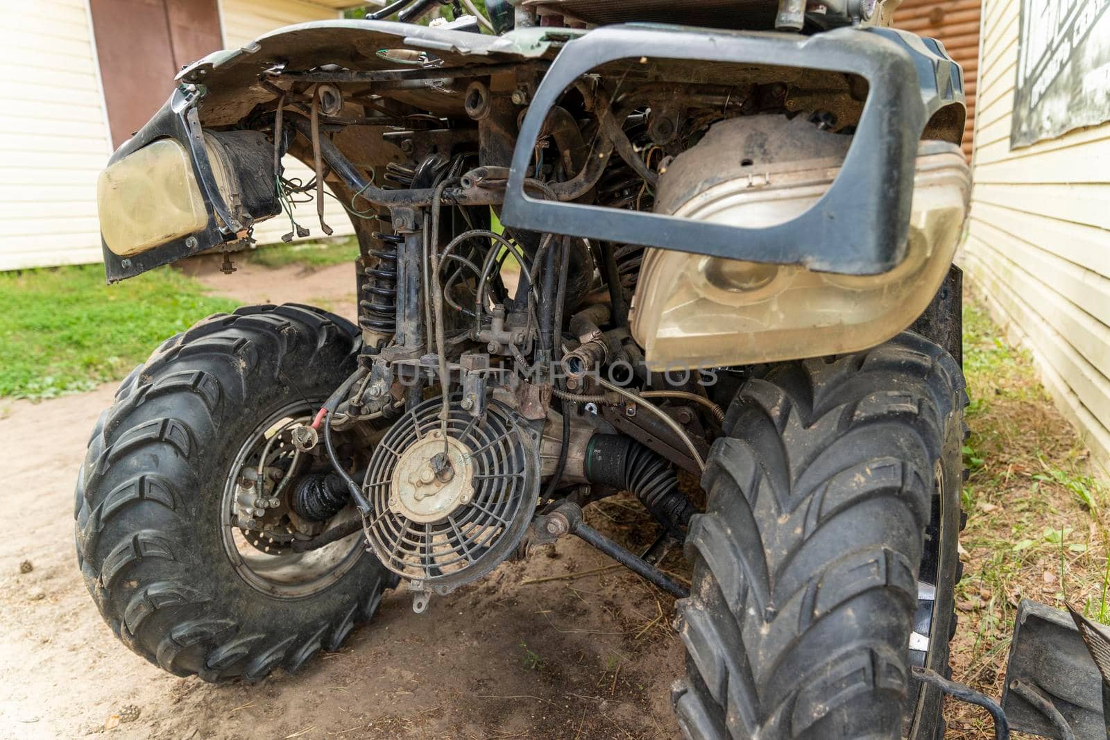 the front part of a broken and disassembled ATV in need of repair. cooling radiator, cooling fan