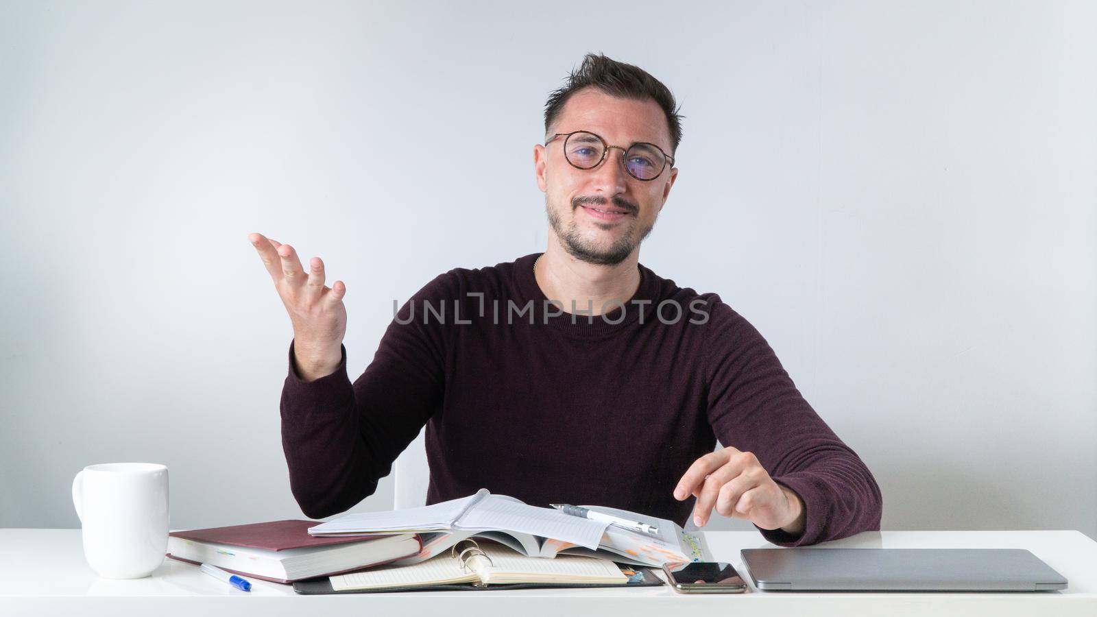 An employee with glasses in the office at a desk with a laptop. High quality photo