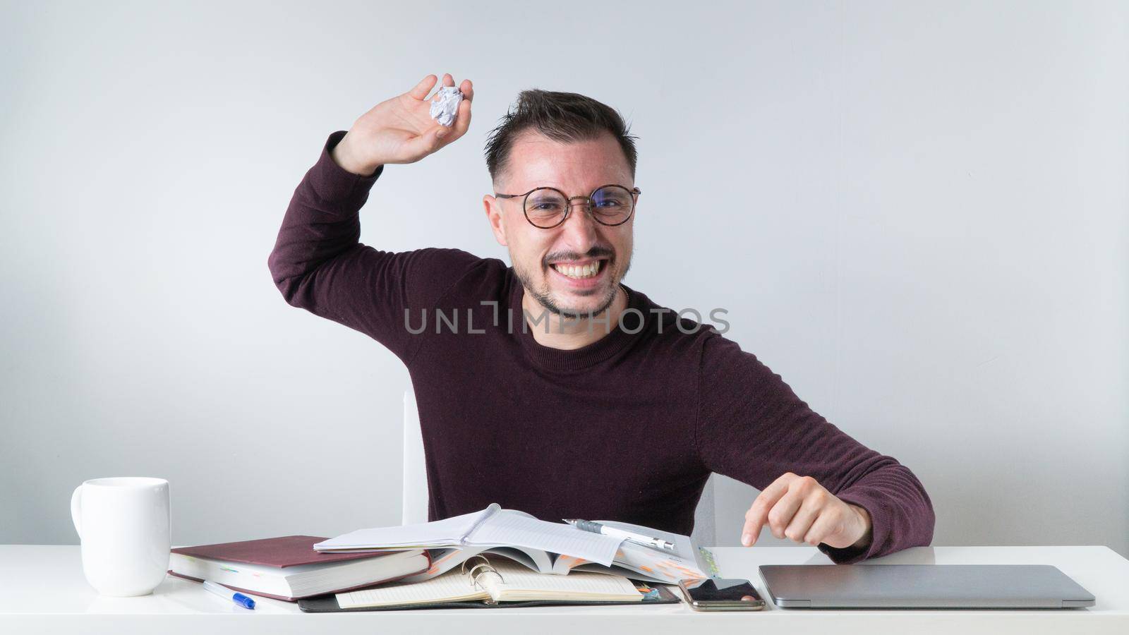 An angry employee throws crumpled paper at his desk. High quality photo