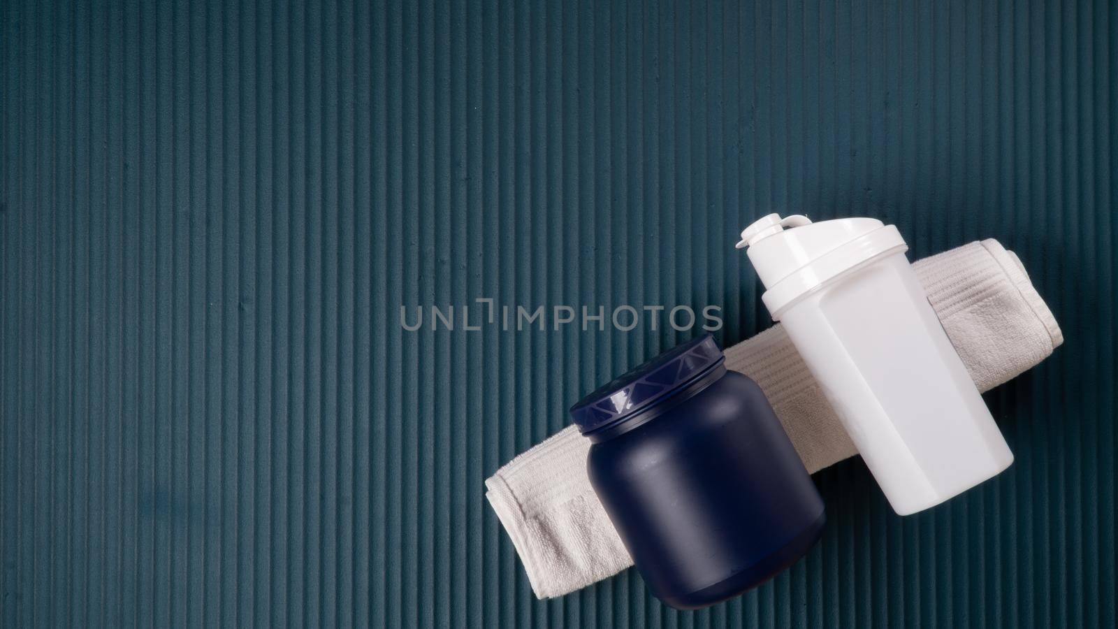 Shaker and a can of sports nutrition on a towel - space for inscription. High quality photo