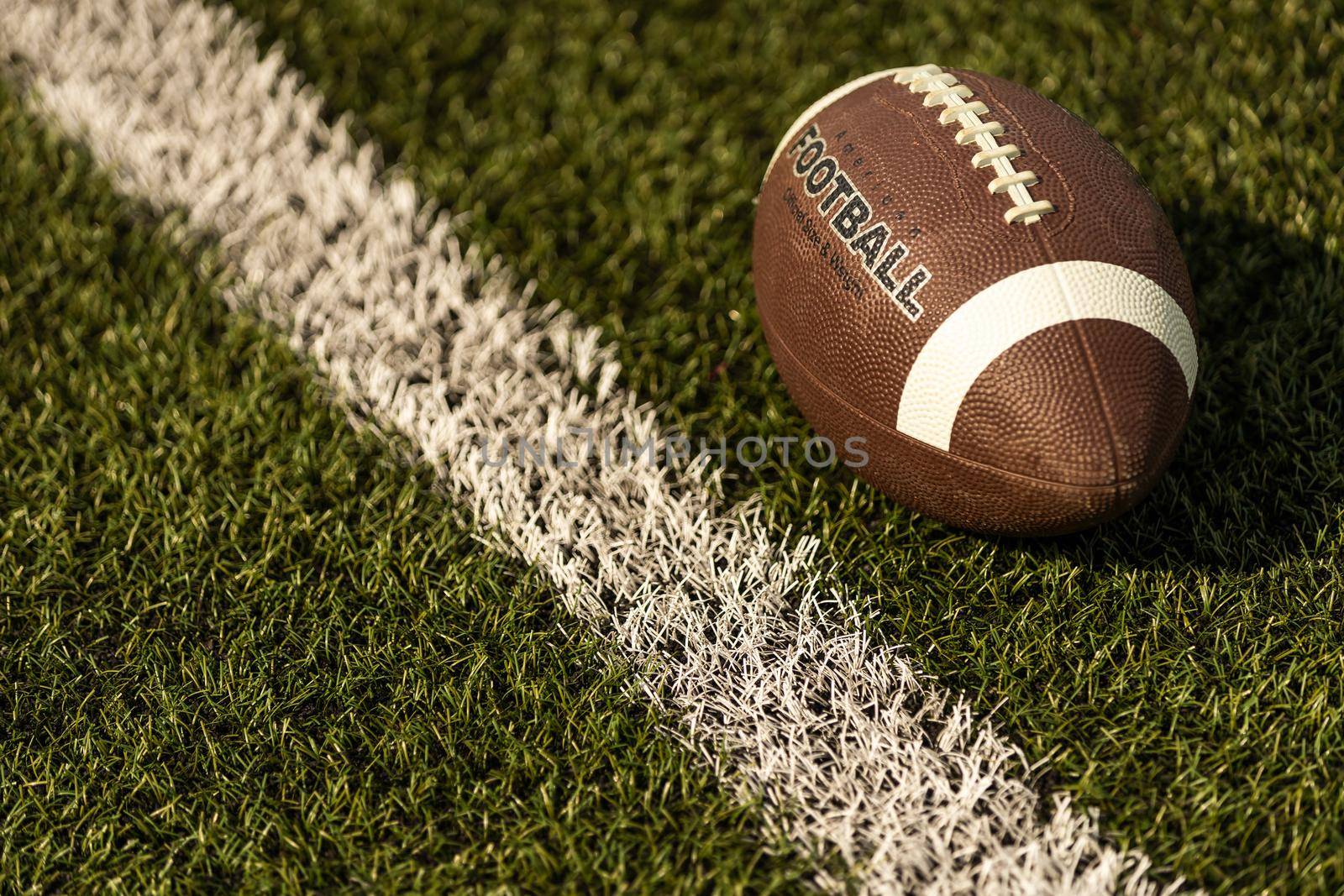 American football ball on the grass of a stadium.