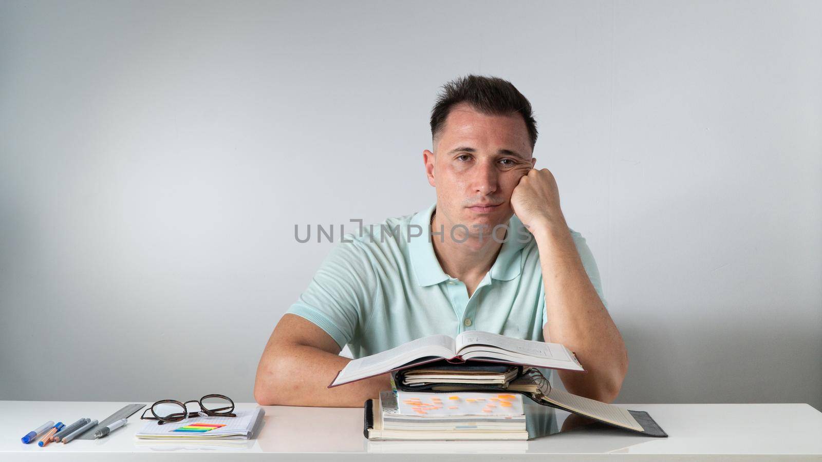 Bored student sits at textbooks and notebooks - study. High quality photo