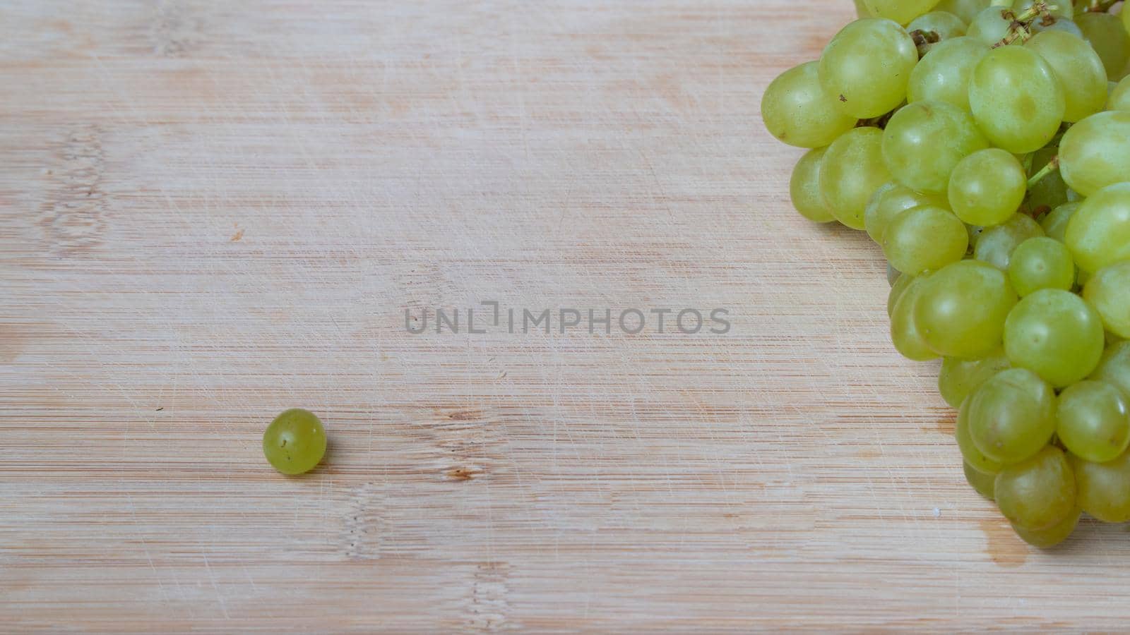 A bunch of green quiche-mish grapes on a wooden background with space for text by voktybre