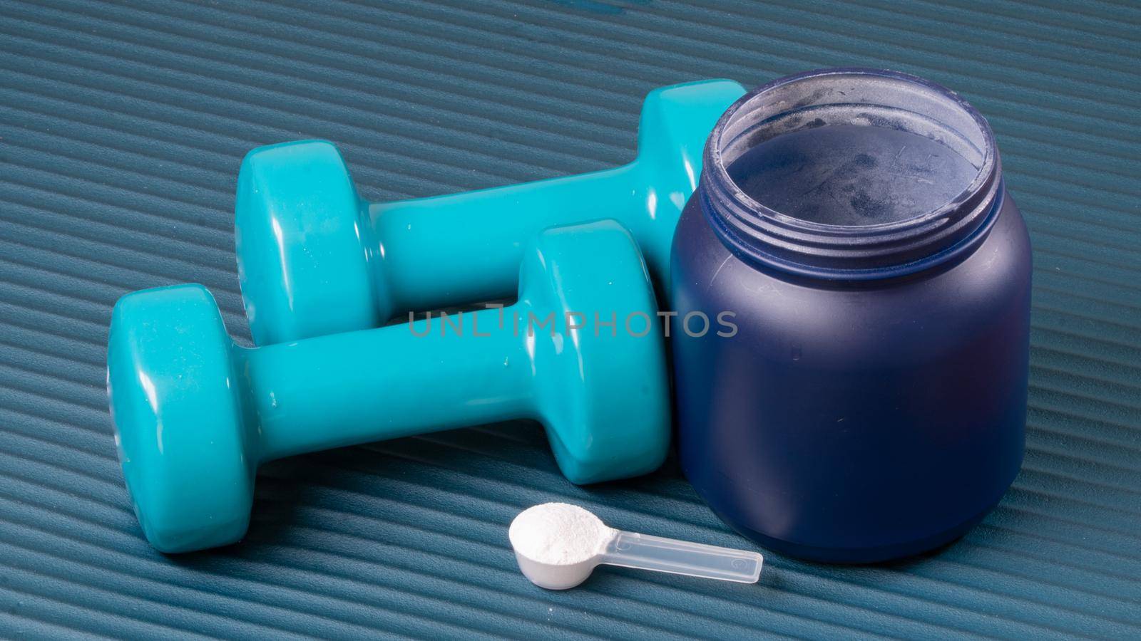 Sports nutrition and dumbbells on the mat for training. High quality photo