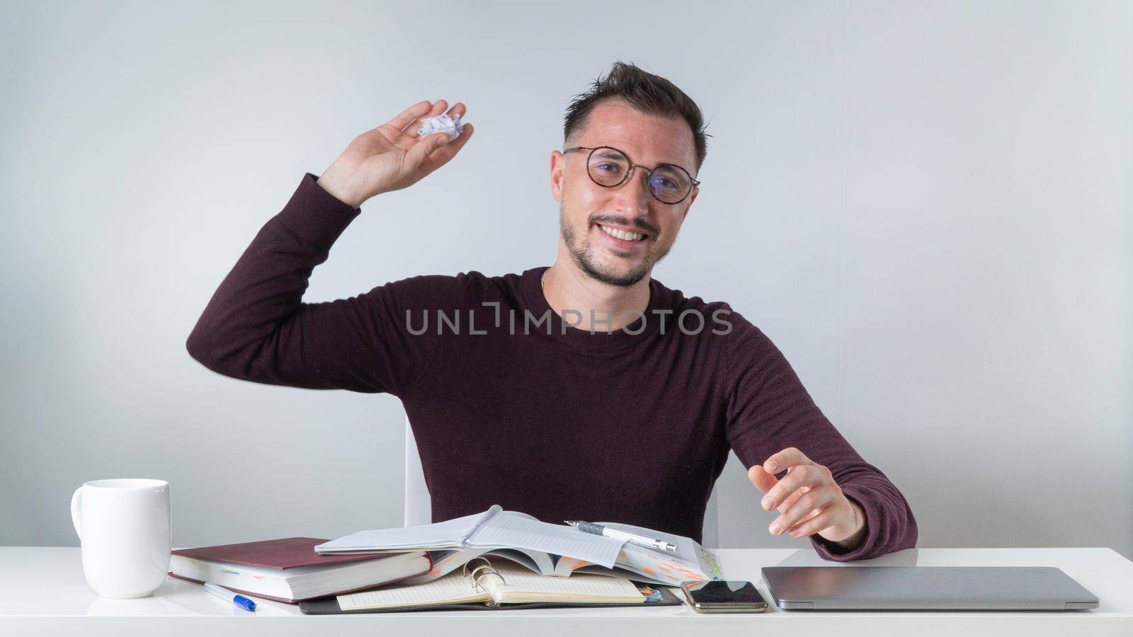 A satisfied employee throws a crumpled lump of paper at a desk in the office by voktybre