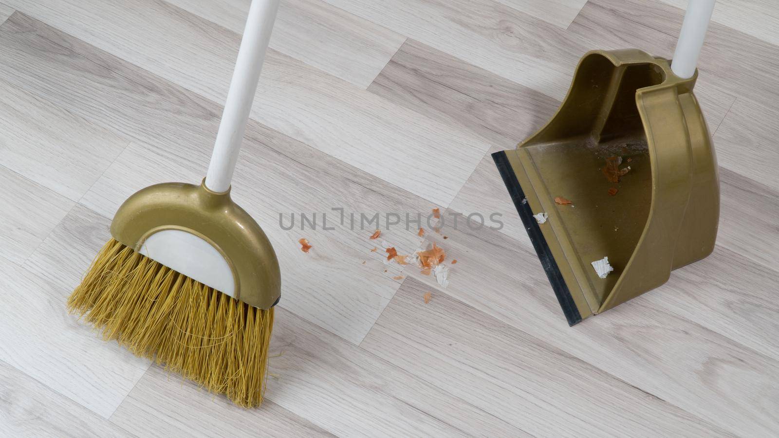 broom brush and scoop sweeping dirt off floor laminate by voktybre