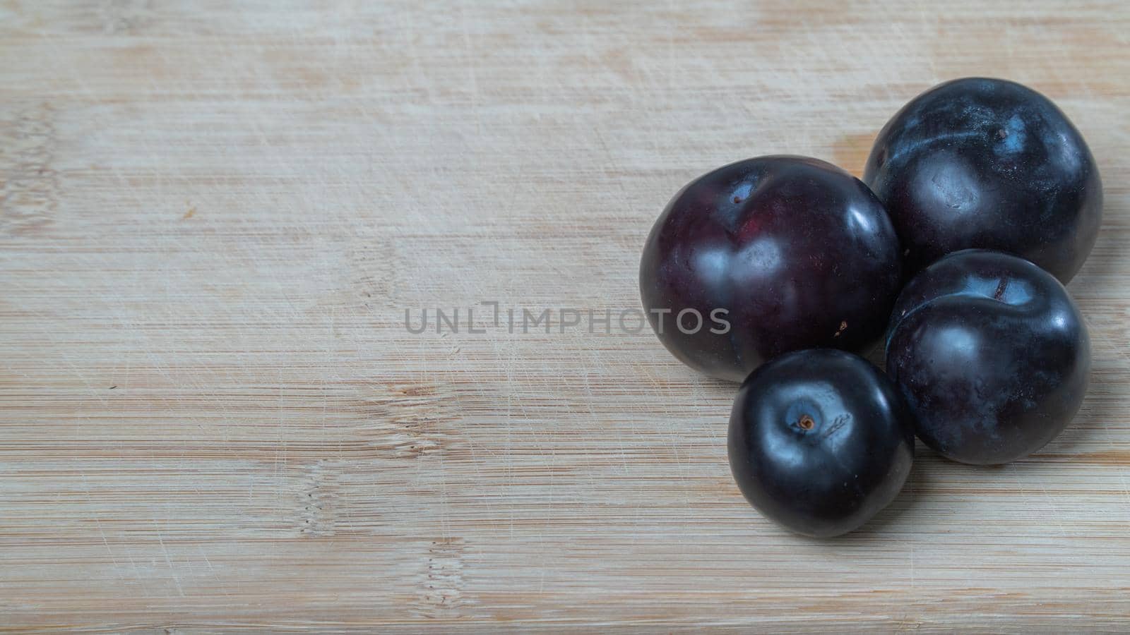 Plum fruits on a wooden board with space for inscription. High quality photo