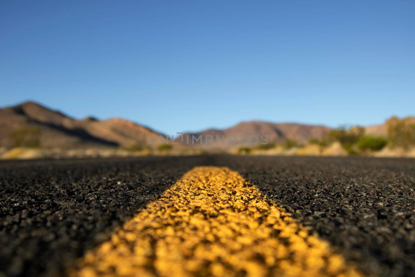 Landscape showing some mountains under a blue clear sky viewed from the asphalt of a road in California