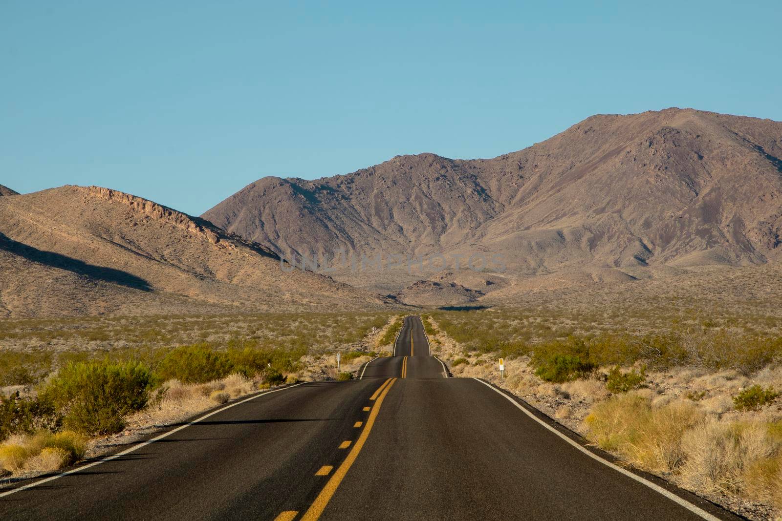 Wavy road and some mountains in the background in Death Valley in the USA