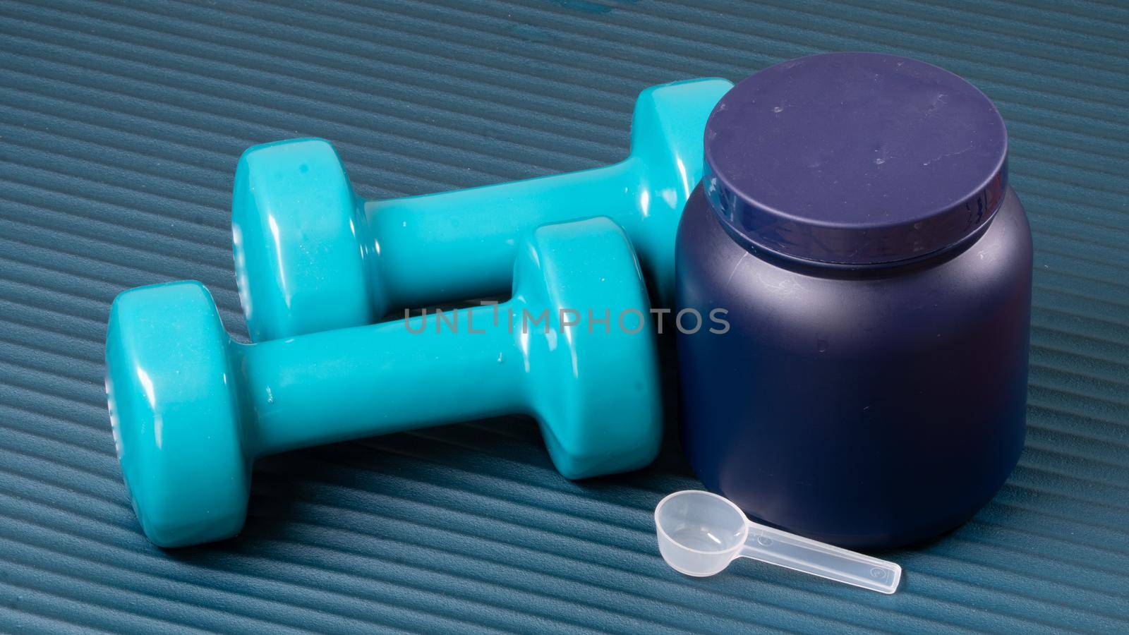 Closed can with sports nutrition, stingy and dumbbells on the mat for training sports background. High quality photo