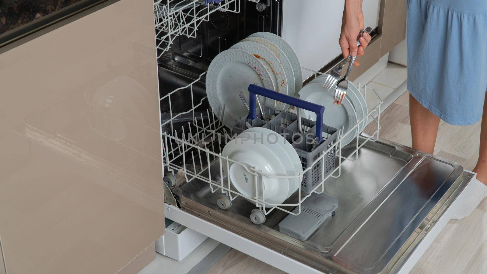 A housewife loads dirty dishes into the dishwasher