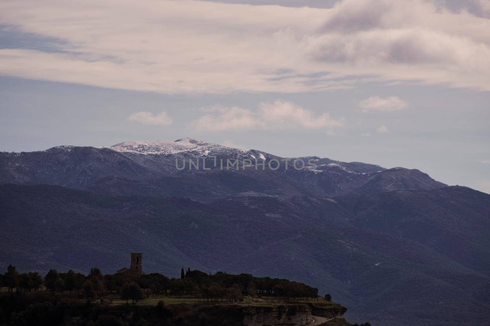 Landscape showing Tona Castle under snowy mountains and cloudy sky in Tona town in Catalonia