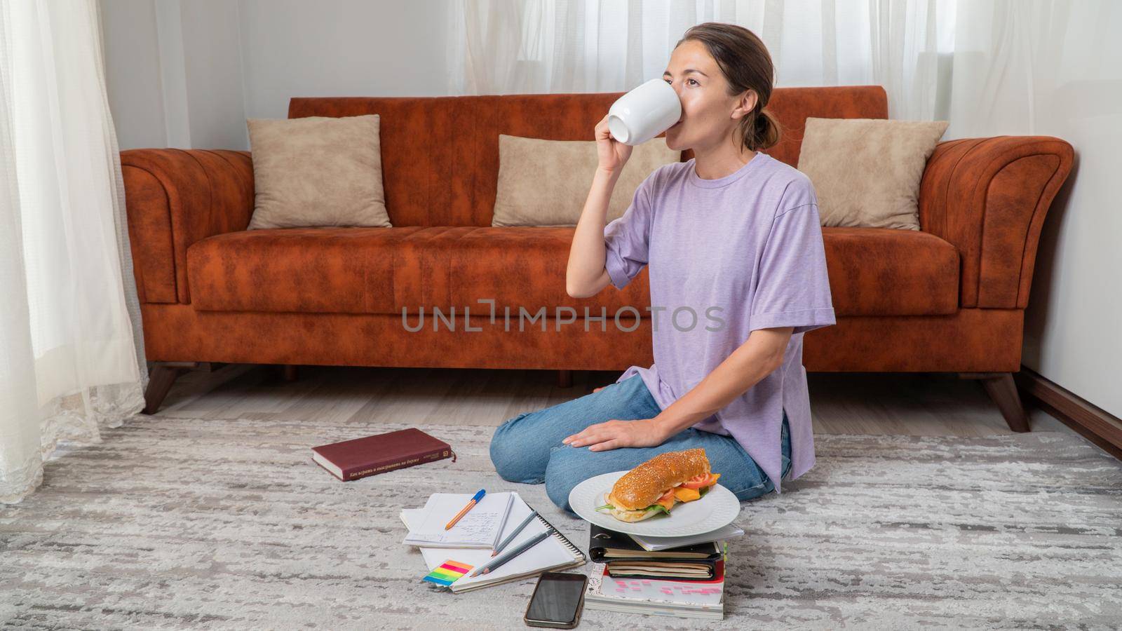 Female student drinks coffee while studying at home by voktybre