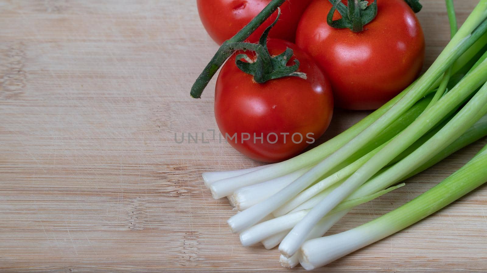 tomatoes on a branch and green onions, vegetables and greens on a wooden background. High quality photo